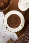 Primer plano vista superior de chocolate caliente con barras de chocolate, polvo y leche - foto de stock