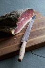 Raw ham with knife — Stock Photo