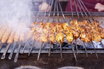 Elevated view of barbecued skewers of meat over embers — Stock Photo