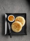 Closeup view of crumpets with marmalade on black square plate — Stock Photo