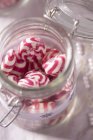 Closeup view of red and white peppermint sweets in storage jar — Stock Photo