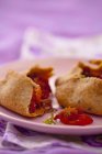 Pacchi di pasticceria integrale con ripieno di pepe e cipolla, dimezzati su piatto viola — Foto stock