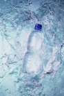 Повышенный вид пластиковой бутылки, падающей в воду — стоковое фото