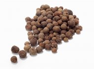 Closeup view of Allspice berries heap on white surface — Stock Photo