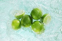 Limes in sparkling water — Stock Photo