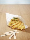 Chips with sprig of rosemary in paper cone — Stock Photo
