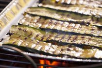 Courgette strips in an aluminium tray on a barbecue — Stock Photo