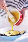 A woman pouring mustard marinade onto sliced aubergine, midsection — Stock Photo