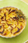 Potato gratin with rosemary on plate over green surface — Stock Photo