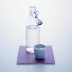 Vista de perto da garrafa com tampa e xícara de água — Fotografia de Stock