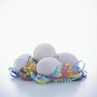 Uova bianche con riccioli di carta tagliuzzata — Foto stock