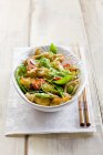 Chicken stirfry with sugar snap peas and noodles in bowl over wooden surface — Stock Photo