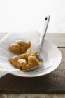Closeup view of deep-fried dough goods with spoon on paper in bowl — Stock Photo