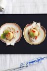 Top view of steamed scallops with herb on valves and black platter — Stock Photo
