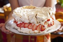 Closeup cropped view of woman holding Pavlova cake with creamy lemon filling and strawberries — Stock Photo