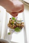 Рука кладе листя фенхелю на салат — стокове фото