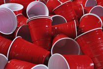 Крупный план пустых красных пластиковых чашек в куче — стоковое фото