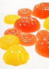 Vista de primer plano de las gelatinas amarillas y anaranjadas en la superficie blanca - foto de stock