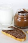 Vue rapprochée de tranche de pain avec tartinade au chocolat et verre de mil — Photo de stock