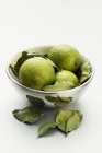 Limes avec feuilles dans un bol en argent — Photo de stock