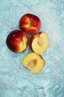 Персики с половинками в воде — стоковое фото