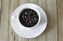Grains de café en tasse blanche — Photo de stock
