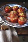 Pomodori ripieni di ragù vegetale in piatto bianco e blu con cucchiaio e forchetta — Foto stock