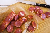 Vista sopraelevata delle fette di Chorizo con un coltello su un tagliere di legno — Foto stock