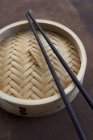 Vista close-up de vapor de bambu com pauzinhos — Fotografia de Stock