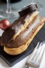 Closeup view of eclair filled with chocolate cream and topped with chocolate decorations — Stock Photo