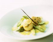 Capesante grigliate su asparagi su piatto bianco — Foto stock