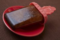 Primo piano vista del ghiacciolo di cola fatto in casa sul piatto rosso — Foto stock