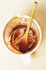 Nahaufnahme von schmutzigem Maßkrug mit Holzlöffel und Resten von Schokoladensauce — Stockfoto