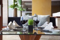 Une table dressée avec quatre couverts et des verres de vin rouge — Photo de stock