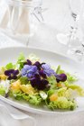 Hojas de ensalada con naranjas y flores comestibles - foto de stock