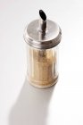 Closeup view of sugar shaker filled with brown sugar on white background — Stock Photo