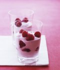 Closeup view of raspberries and yogurt in glasses — Stock Photo