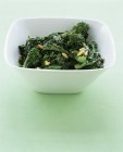 Sautierte Brokkolirabe in weißer Schüssel über grüner Oberfläche — Stockfoto