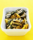 Chargrilled courgette and yellow peppers in white bowl over yellow surface — Stock Photo