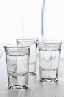 Vista de perto de três copos de Ouzo com garrafa de água — Fotografia de Stock
