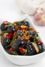 Olive marinate con rosmarino, aglio e peperoncino su piatto bianco — Foto stock