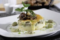 Snails with potatoes and broad beans with mint all-i-oli  on white plate — Stock Photo