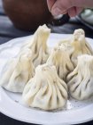 Cropped view of a hand spicing Khinkhali stuffed dumplings — Stock Photo