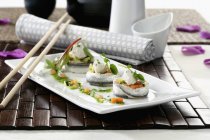 Рыбные рулеты с овощами на белой тарелке с палочками — стоковое фото