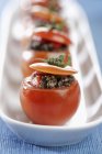 Detail of cherry tomatoes stuffed with tapenade of peppers on white plate over blue surface — Stock Photo