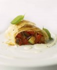 Vegetable strudel with tomatoes and courgette on white plate — Stock Photo