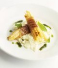 Grilled white asparagus wrapped in ham, on risotto on white plate — Stock Photo