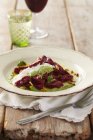 Beetroot gnocchi on white plate over towel with fork — Stock Photo