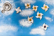 Top view of puff pastry pinwheels with icing sugar on blue surface — Stock Photo