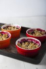 Closeup view of berry crumbles in red bowls on tray — Stock Photo